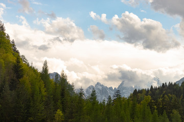 Austria. Alpine mountain range behind the forest. Mountains peeking out from behind the treetops.