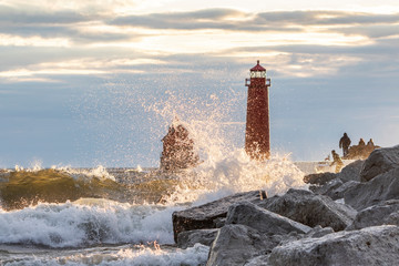 lighthouse with splashing waves over rocks