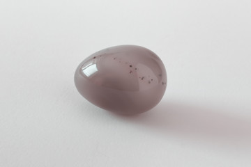 Single one Easter egg made of glossy polished precious milky brown red opal stone with inclusions on white background.