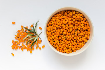 Top view of a bowl of sea buckthorn berries on white background.