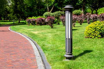 ground street lantern near winding footpath alley with a drainage system and a walkway on park with...