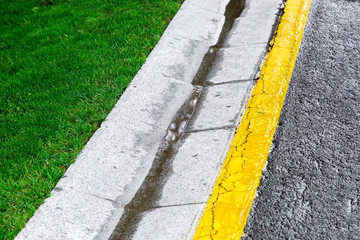 flowing rainwater in the canal is a cement ditch of a drainage system on the side of an asphalt...
