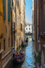 Obraz na płótnie Canvas Narrow canal in Venice, Italy, with gondolas and historic houses, in a beautiful sunny day.