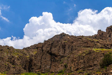 an amazing sky with clouds on top of the rocky hill