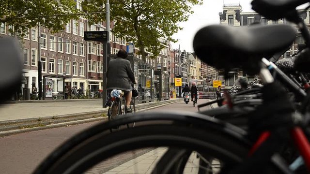 Amsterdam, Holland, August 2019.A particular point of view: from the blurred frame and saddle of a parked bike we see the cyclists passing on the cycle path. More to the left the tram stop.