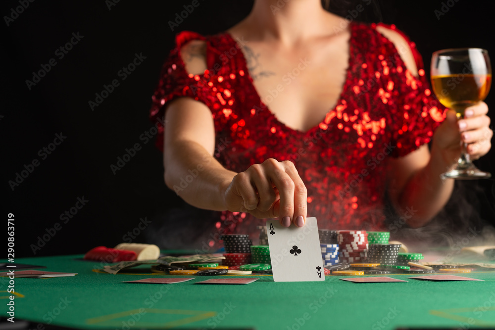 Wall mural girl in evening dress plays poker draws a card in a casino. focus on the card and focus