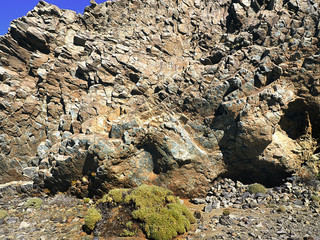 A high natural lava stone wall, consisting of colorful cuboid segments