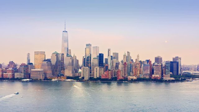 Drone footage with slow approach towards New York City skyline above Hudson river, at sunset