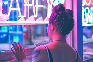 Woman looking through a window with neon lights