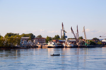       Loading port cranes on the pier on the river.Horizontally.