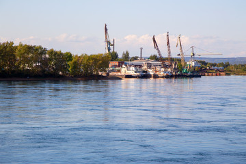      Loading port cranes on the pier on the river.Horizontally.