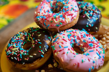  donuts, close-up photo with selective focus - assorted donuts with chocolate frosted, pink glazed and sugary sprinkles. 