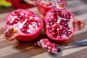 pomegranate fruit sliced on a wooden cutting board. Ripe pomegranate closeup with selective focus