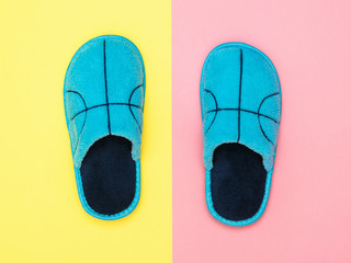 Beautiful blue house Slippers on pink and yellow background. The view from the top. Flat lay.