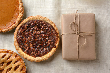 Three Holiday Pies, Pecan, Pumpkin, and Apple with wrapped package. 