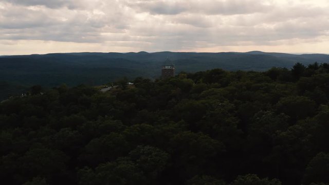Aerial paralex view of Bear mountain top with cloudy sky and sunrays breaking thru 4k