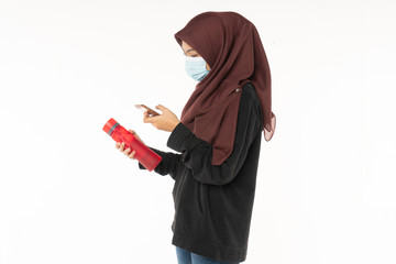 Asian woman wearing face masks due to the haze in situation while holding a red bottle isolated on white