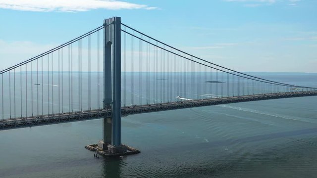 Aerial view of the Verrazano Bridge as the drone camera pans right viewing Staten Island and the waters below on a sunny morning, orbit 3