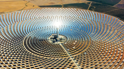 Solar panels in a large thermal circular power plant with the reflection of the sunlight in the panels. Renewable and pollution-free energy in a solar farm in Spain- aerial view with a drone - environ - 290877531