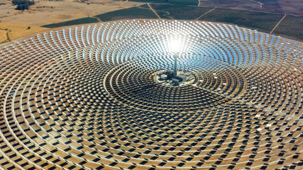 Solar panels in a large thermal circular power plant with the reflection of the sunlight in the panels. Renewable and pollution-free energy in a solar farm in Spain- aerial view with a drone - environ - 290877534