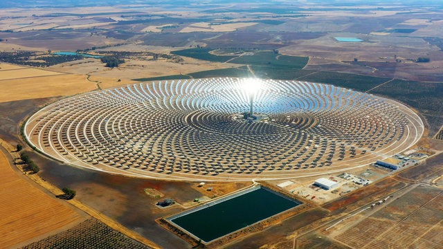 Aerial view of a large circular power plant of solar panels in Spain. There is the reflection of the sun in the the panels which produce renewable energy - environment concept