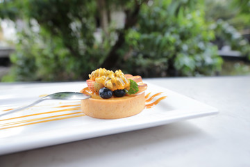 Fruit pie on white ceramic plate. Strawberry, blueburry, passion fruit assorted on crispy baked pastry cup with creamy on top