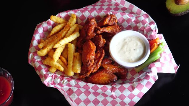 wings in buffalo sauce accompanied by fries, cucumber, carrot, dressing and catsup sauce