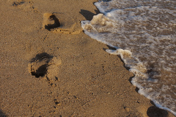 A row of footprints in the sand on a beach in the summertime, seashore. The concept of history, beach holiday