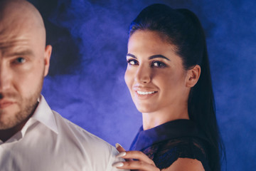 the first and second plan: a beautiful brunette leans on the shoulder of a man. The woman behind the Jock in the smoke. The concept of entrepreneurship, business development, hair, makeup, show of for
