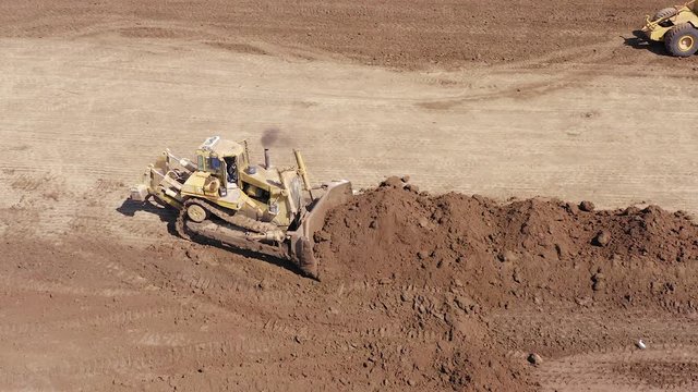 Bulldozer pushing large amount of fresh soil, Aerial follow footage.
