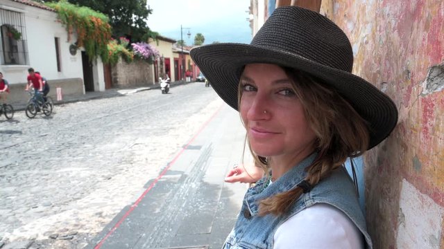 4K Video close up of a beautiful woman leaning against a wall, smiling at the camera in the streets of Antigua Guatemala.