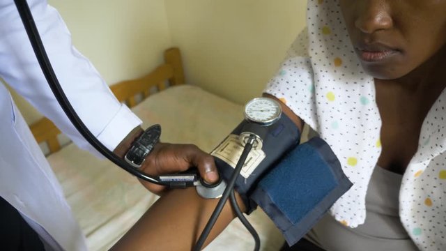 Close up shot of a sphygmomanometer and a stethoscope on an African woman's arm.