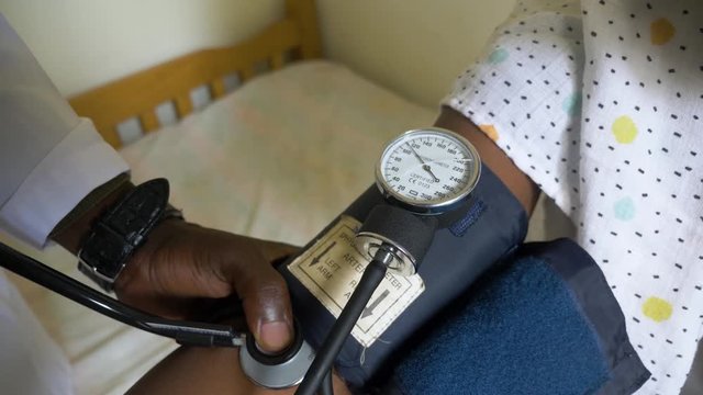 Close up shot of a sphygmomanometer checking the blood pressure of an African patient in a small health clinic.
