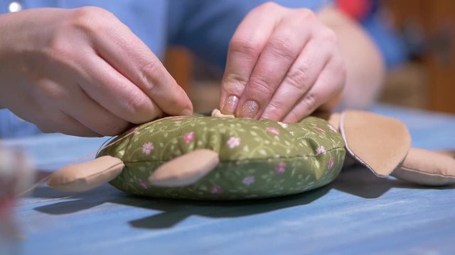 woman sews a rag doll with her hands