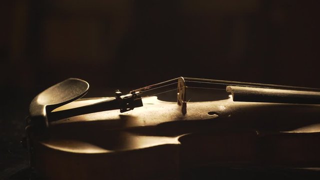 close up of old violin, dramatic light changes over the instrument , classical symphony music video footage