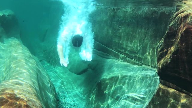 epic underwater slow motion of a young man diving into crystal clear water in the nature outdoors. diving into the river in verzasca valley in lavertezzo switzerland