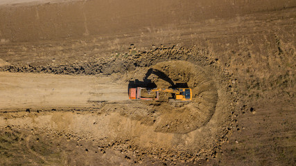 Aerial shot of excavator pours sand into the truck. On the construction site top view. Shooting from the drone. © Quatrox Production