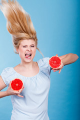 Woman holding red grapefruit having crazy windblown hair