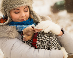 Woman hug warming her little dog in winter