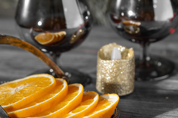 Slices of orange on a background of glass goblets and a decorative candle.