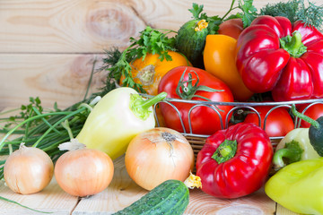 Natural homegrown food concept. Assorted fresh vegetables from new harvest collected in a wicker basket on wooden background.