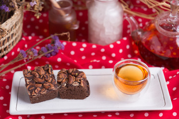 Tea pot and tea cup on wood table with honey and suagr in mag with flower basket on red cloth napkin, with butter cookies and brownies