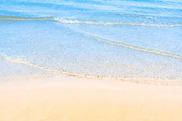 Ocean wave on tropical beach with golden sand and ripple of water splash from emerald blue-green sea water during summer vacation. 