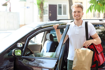 Worker of food delivery service near car outdoors