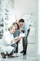 Obraz premium Pharmacy employee pointing at the tablet to man and kid