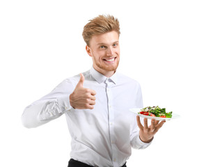 Handsome waiter with salad showing thumb-up on white background