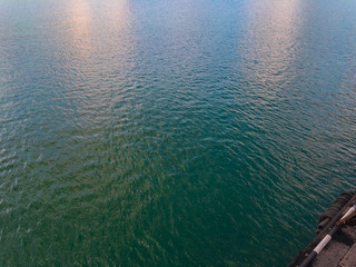 Colorful greenish-turquoise water of the sea with light ripples and sunny glare on a summer day...