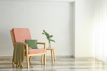 Soft armchair with eucalyptus branches in vase on table