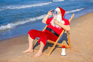 Happy Santa Claus with cocktail and mask resting at sea resort