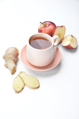 Cup of hot tea with apple and ginger on white background